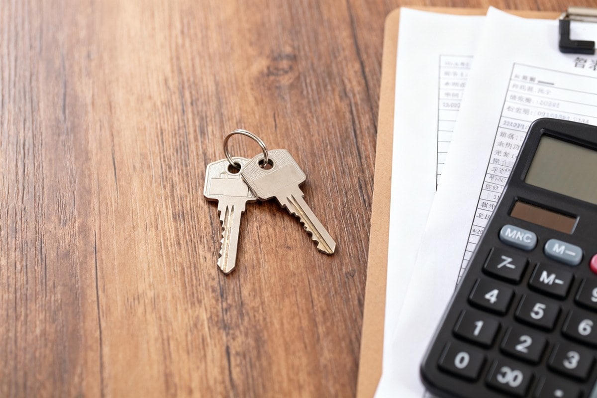Clés de maison, documents financiers et calculatrice sur une table en bois